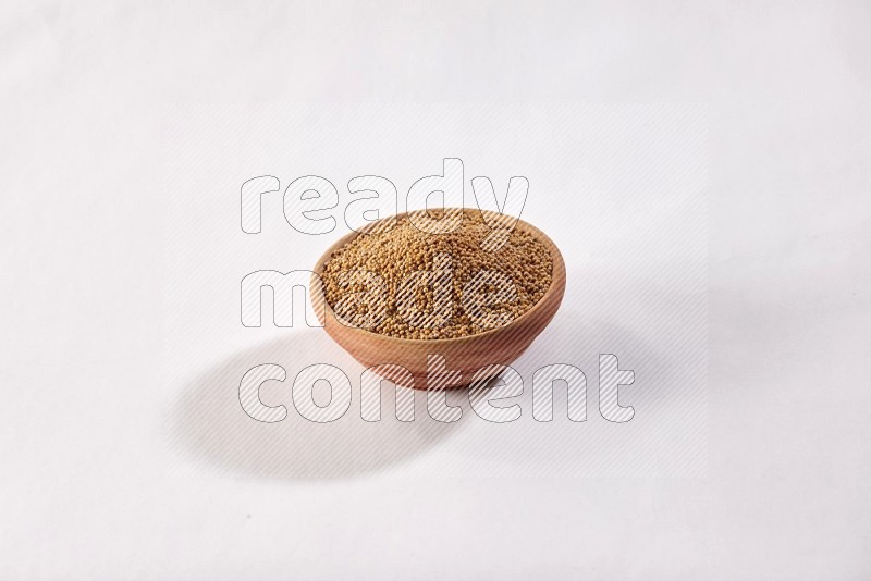 A wooden bowl full of mustard seeds on a white flooring in different angles