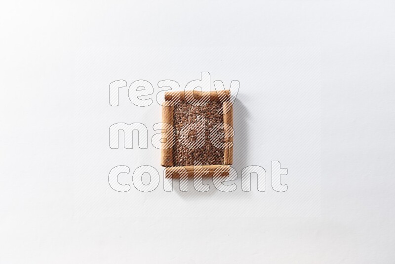 A single square of cinnamon sticks full of flaxseeds on white flooring