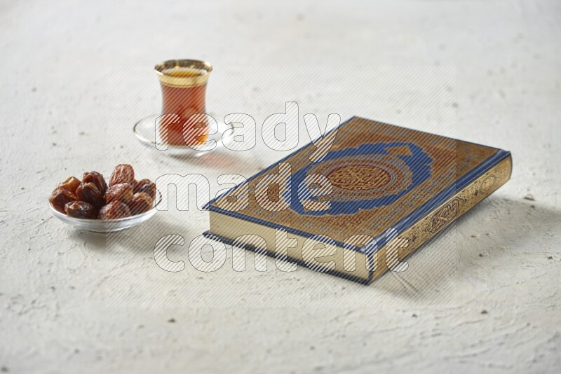 Quran with dates, prayer beads and different drinks all placed on textured white background