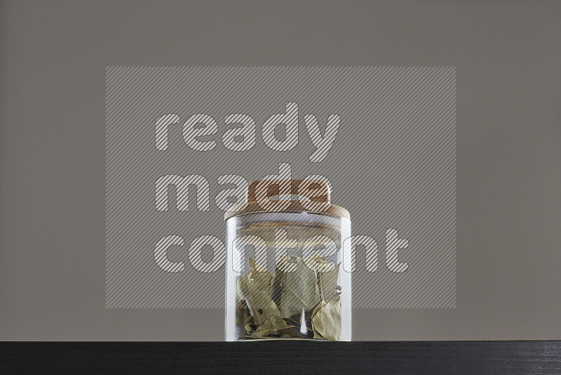 Bay laurel leaves in a glass jar on black background