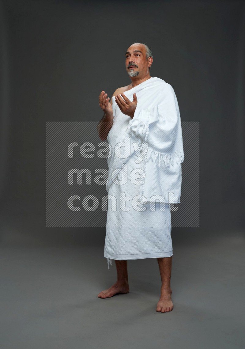 A man wearing Ehram Standing dua'a on gray background