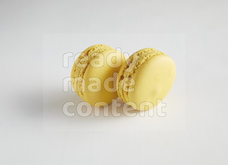 45º Shot of two Yellow Lemon macarons on white background