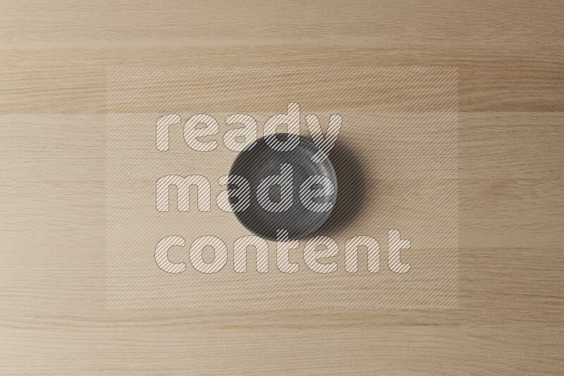 A black pottery bowl on light wooden background