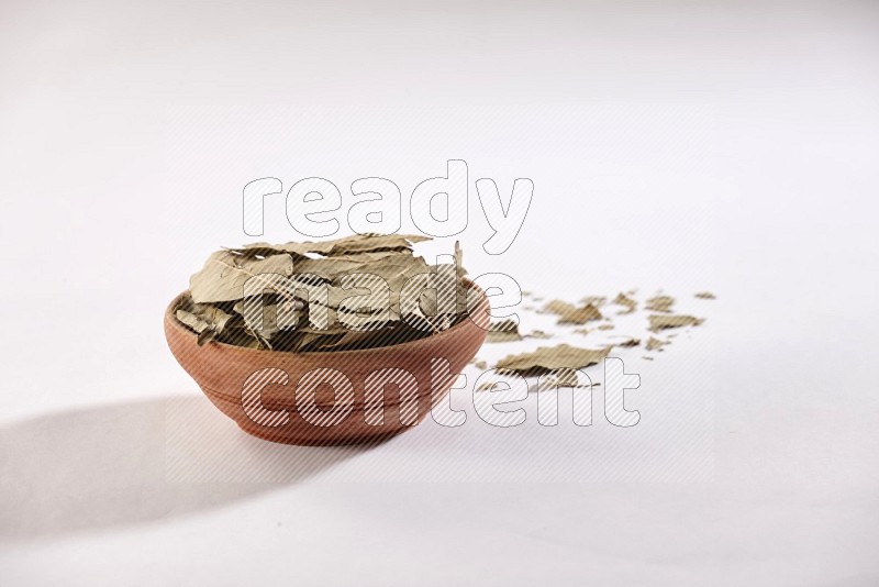 A wooden bowl filled with laurel bay on white flooring in different angles