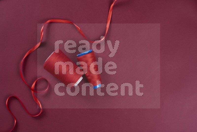 مجموعة من أدوات الخياطة والتفصيل حمراء اللون على خلفية حمراء