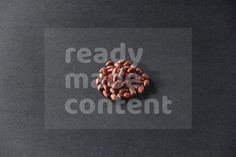 A bunch of red skin peanuts on a black background in different angles