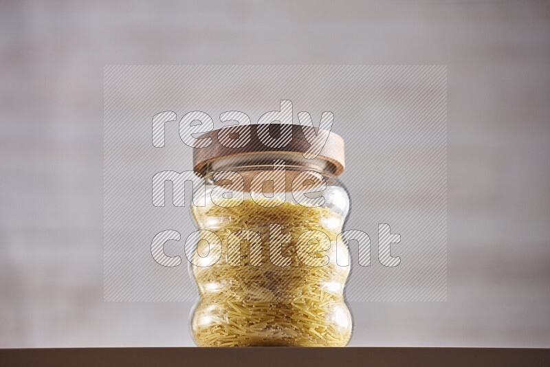 Raw pasta in glass jars on beige background