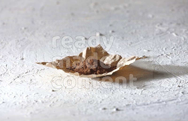 Cloves powder on crumpled piece of paper on a textured white flooring