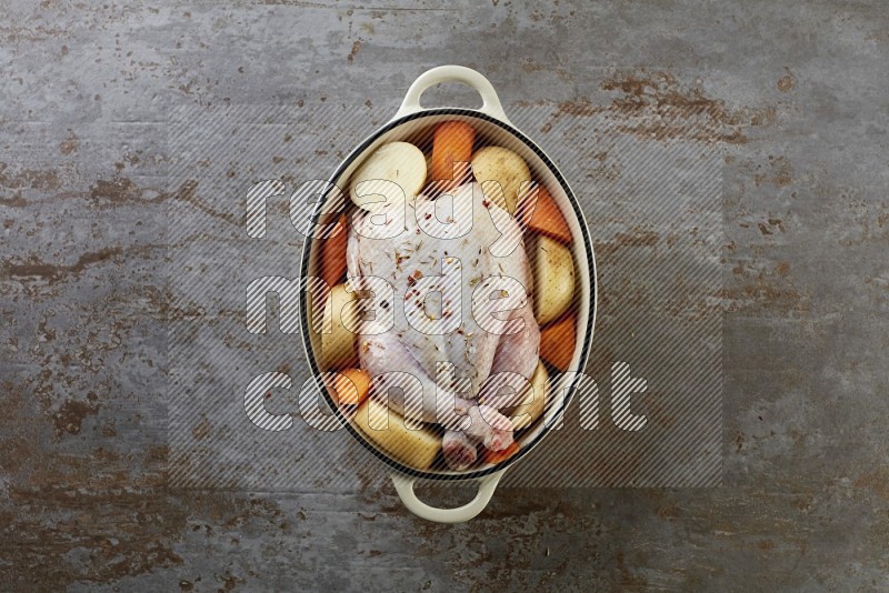 whole raw chicken on in a white ceramic pot direct on a rustic grey background