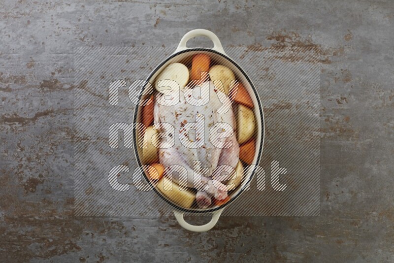 whole raw chicken on in a white ceramic pot direct on a rustic grey background