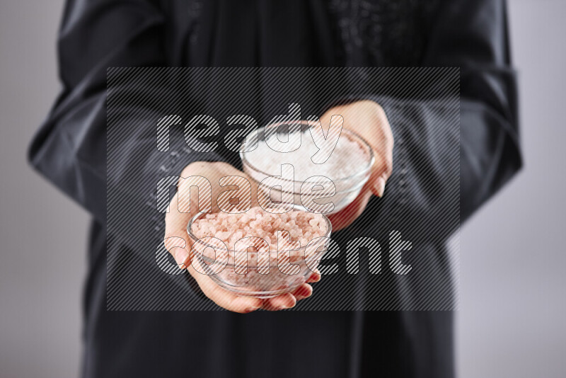 Woman in abaya holding different kinds of spices in different positions