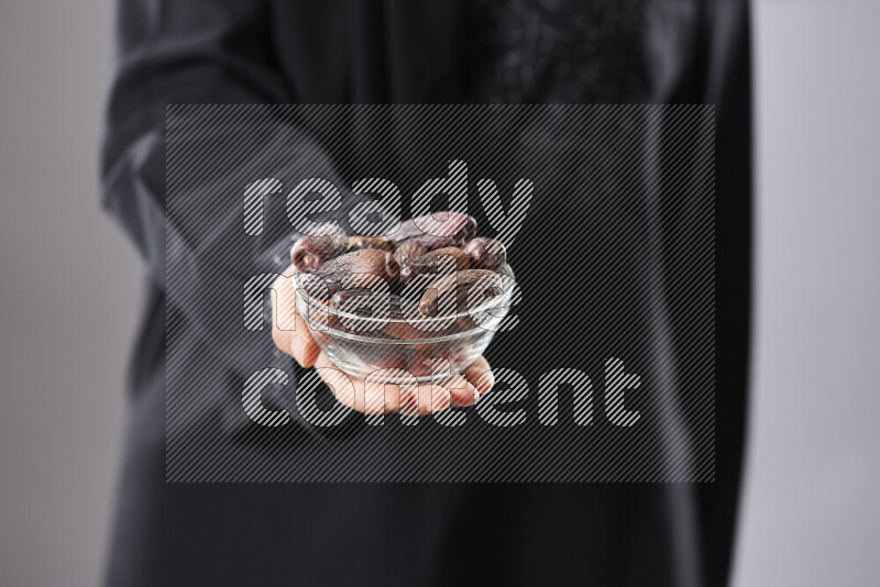 Woman in abaya holding dates in different positions