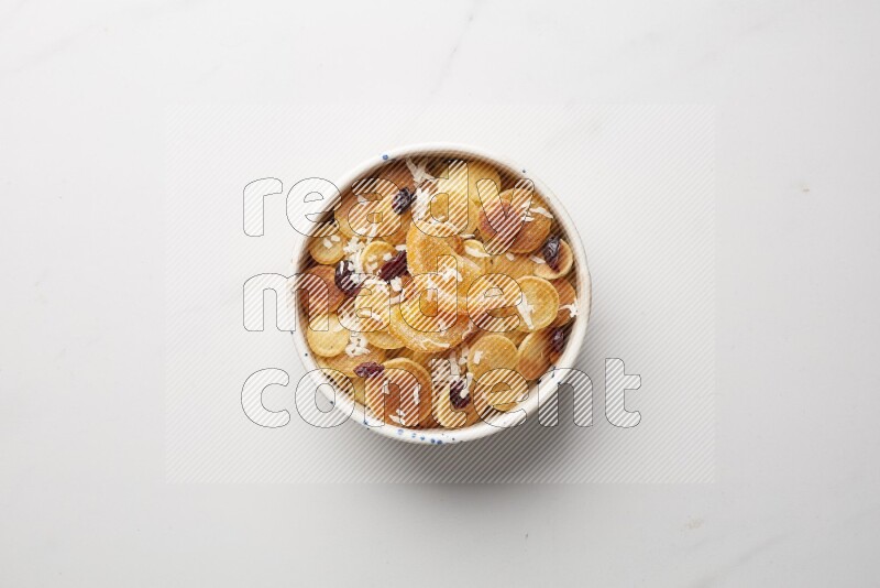 Top-view shot of orange candy cereal pancakes in a round bowl on white background