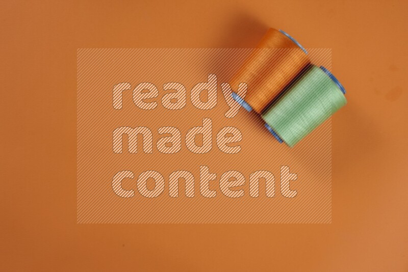 مجموعة من أدوات الخياطة والتفصيل خضراء وبرتقالية اللون على خلفية برتقالية