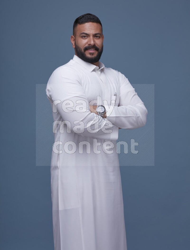 A man Posing in Blue Background wearing a Saudi Thob