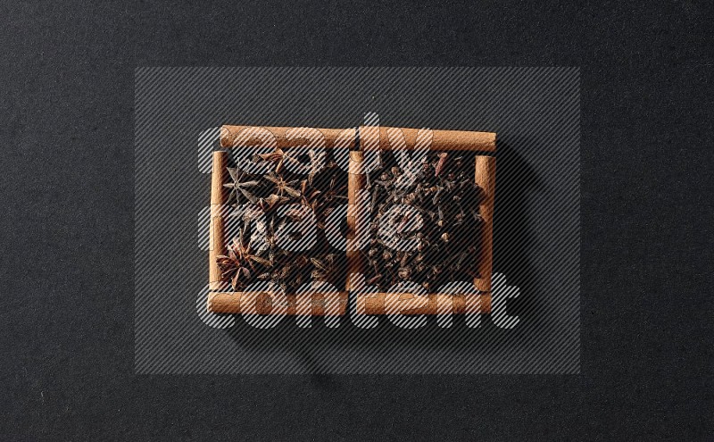 2 squares of cinnamon sticks full of star anise and cloves on black flooring
