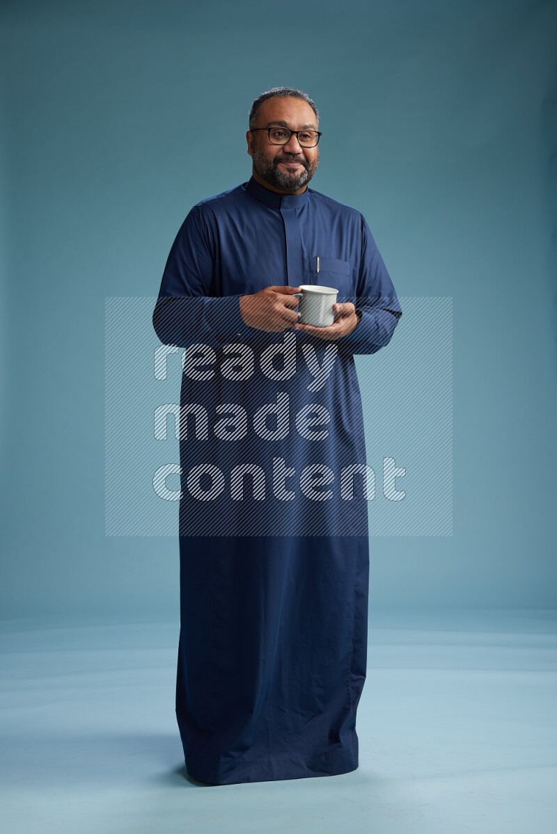 Saudi Man without shimag Standing drinking coffee on blue background