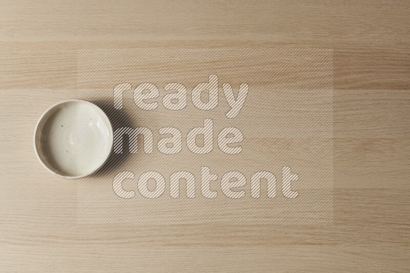 A white pottery bowl on light wooden background