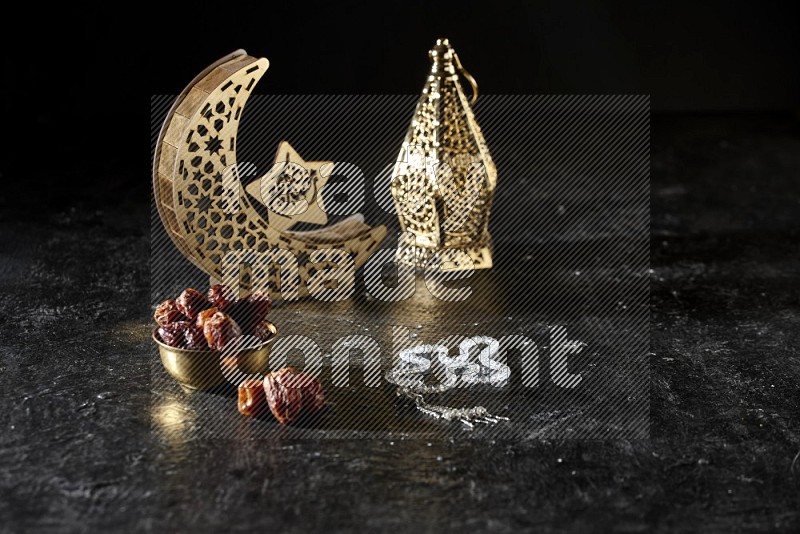 Dates in a metal bowl with prayer beads beside golden lanterns in a dark setup