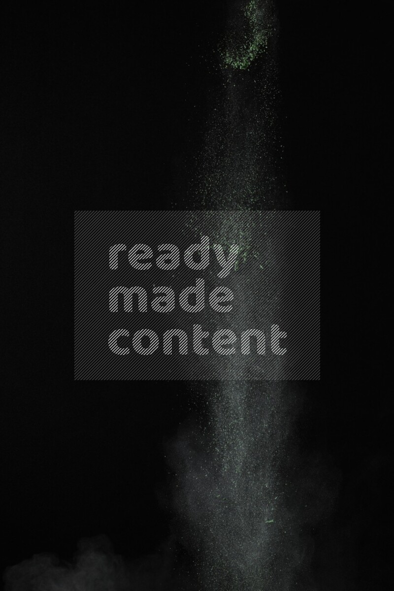 A side view of green powder explosion on black background