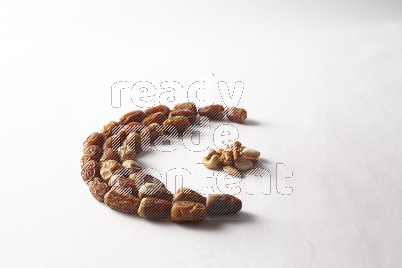 Dates in a crescent shape with nuts on white background