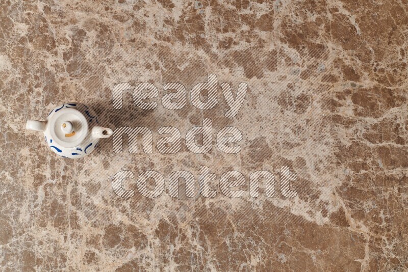 A pottery teapot on beige marble background