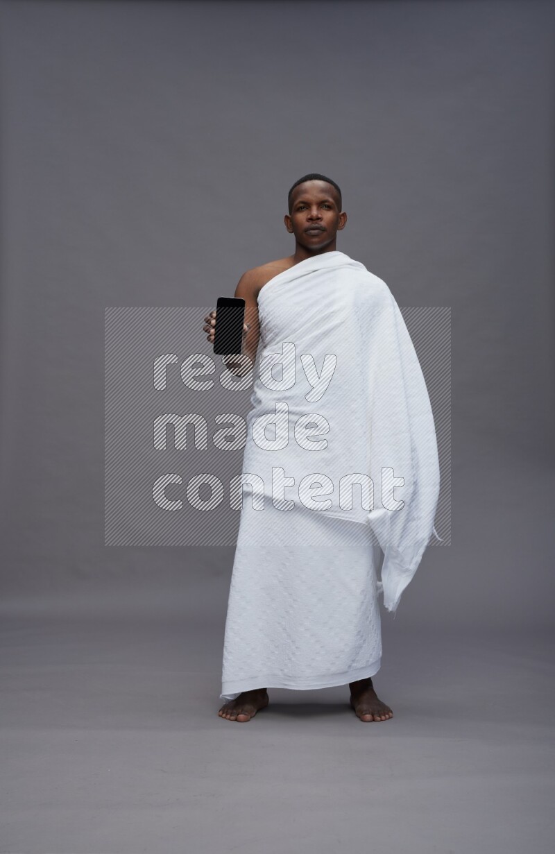 A man wearing Ehram Standing showing phone to camera on gray background