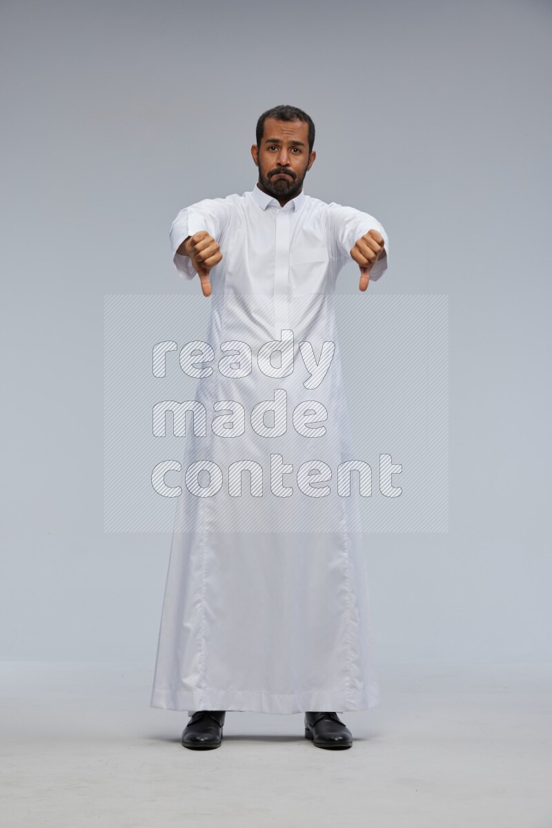 Saudi man Wearing Thob standing interacting with the camera on Gray background