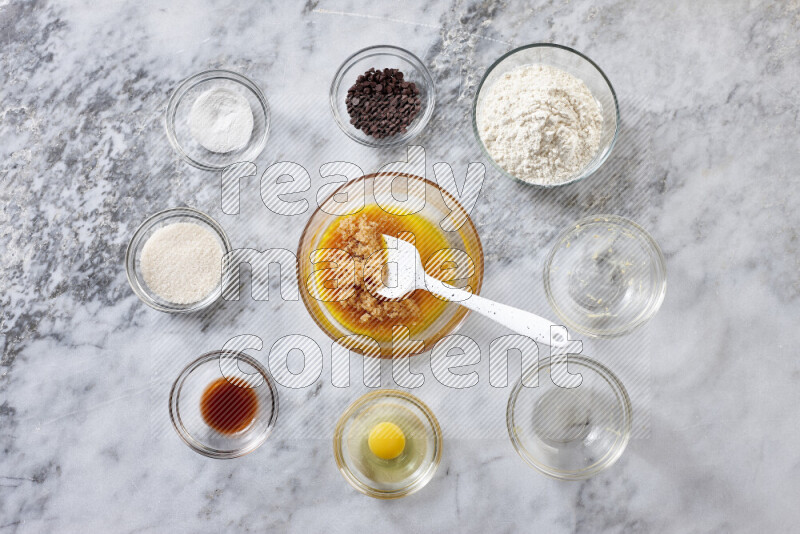 Cookies step by step with its ingredient, flour, butter, brown sugar, egg, vanilla extract, white sugar, chocolate chips and baking soda on grey marble background