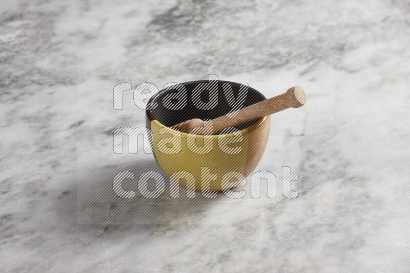 Multicolored pottery bowl with wooden honey dipper in it on grey marble background