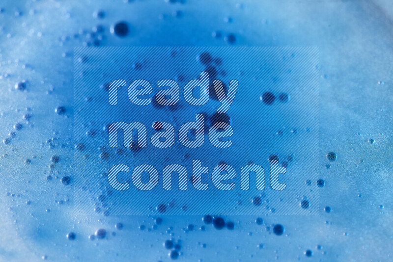 لقطات مقربة لقطرات ألوان مائية زرقاء على سطح الزيت على خلفية زرقاء