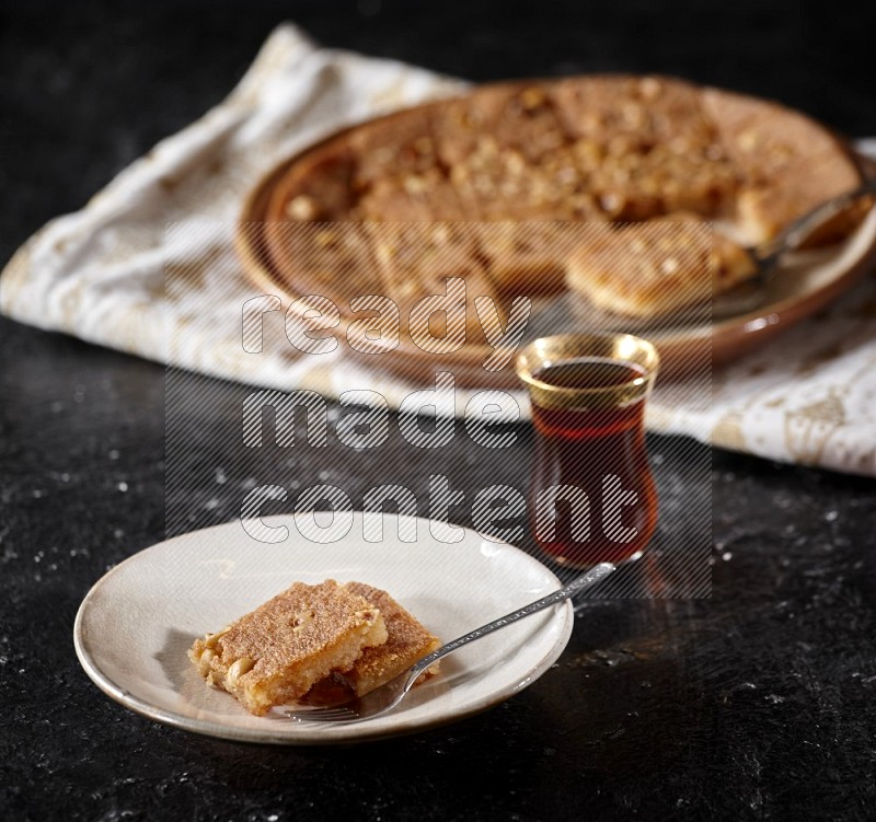 Basbousa with tea in a dark setup