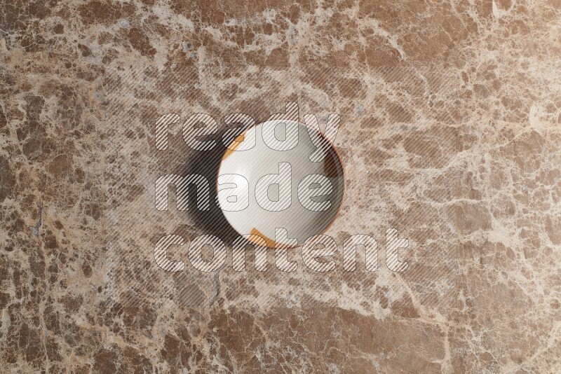 A multicolored pottery bowl on beige marble background