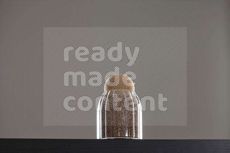 Brown lentils in a glass jar on black background