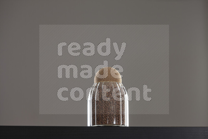 Brown lentils in a glass jar on black background