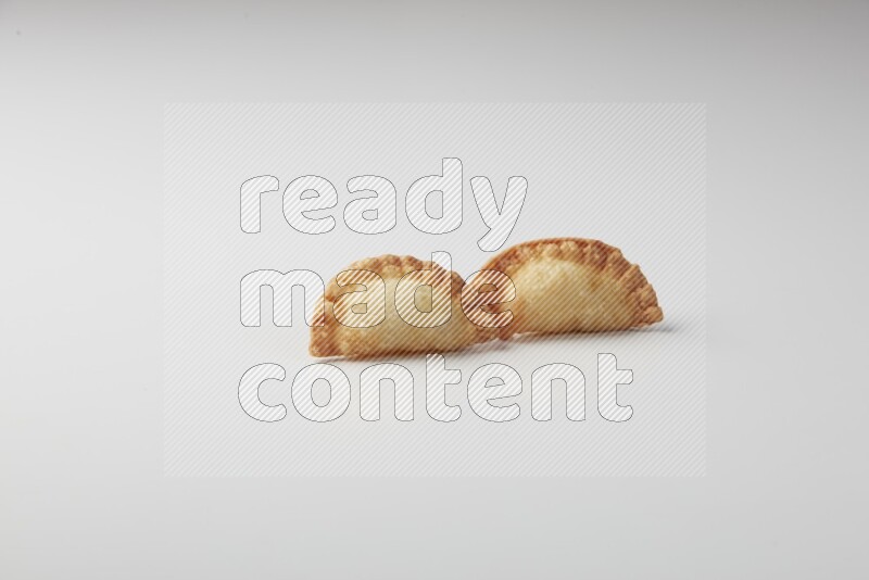 Two fried sambosas on a white background