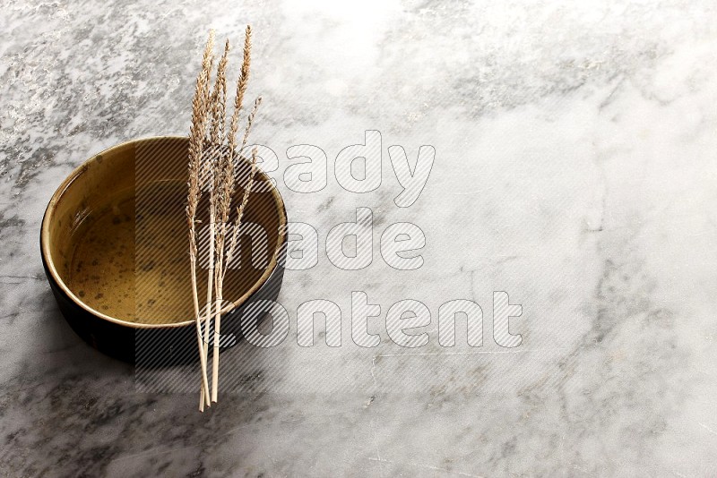 Wheat stalks on Multicolored Pottery Oven Plate on grey marble flooring, 45 degree angle