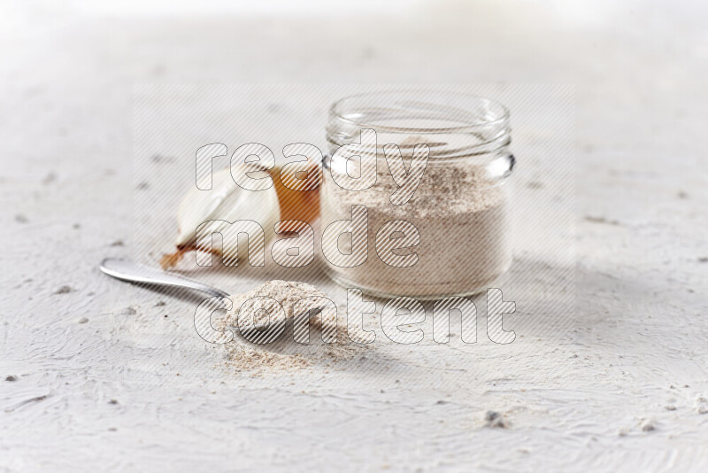 A glass jar full of onion powder on white background