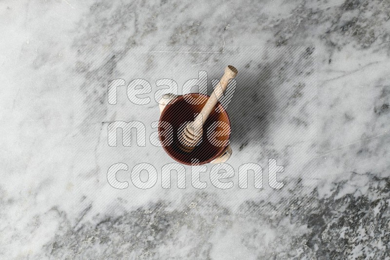 Decorative Pottery Pot with wooden honey handle in it, on grey marble flooring, Top View