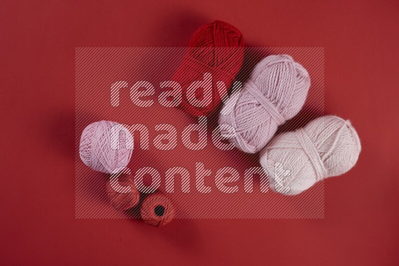 A pink and red collection of sewing and tailoring tools arranged on a red background