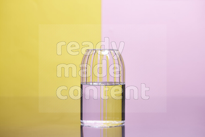 The image features a clear glassware filled with water, set against yellow and rose background