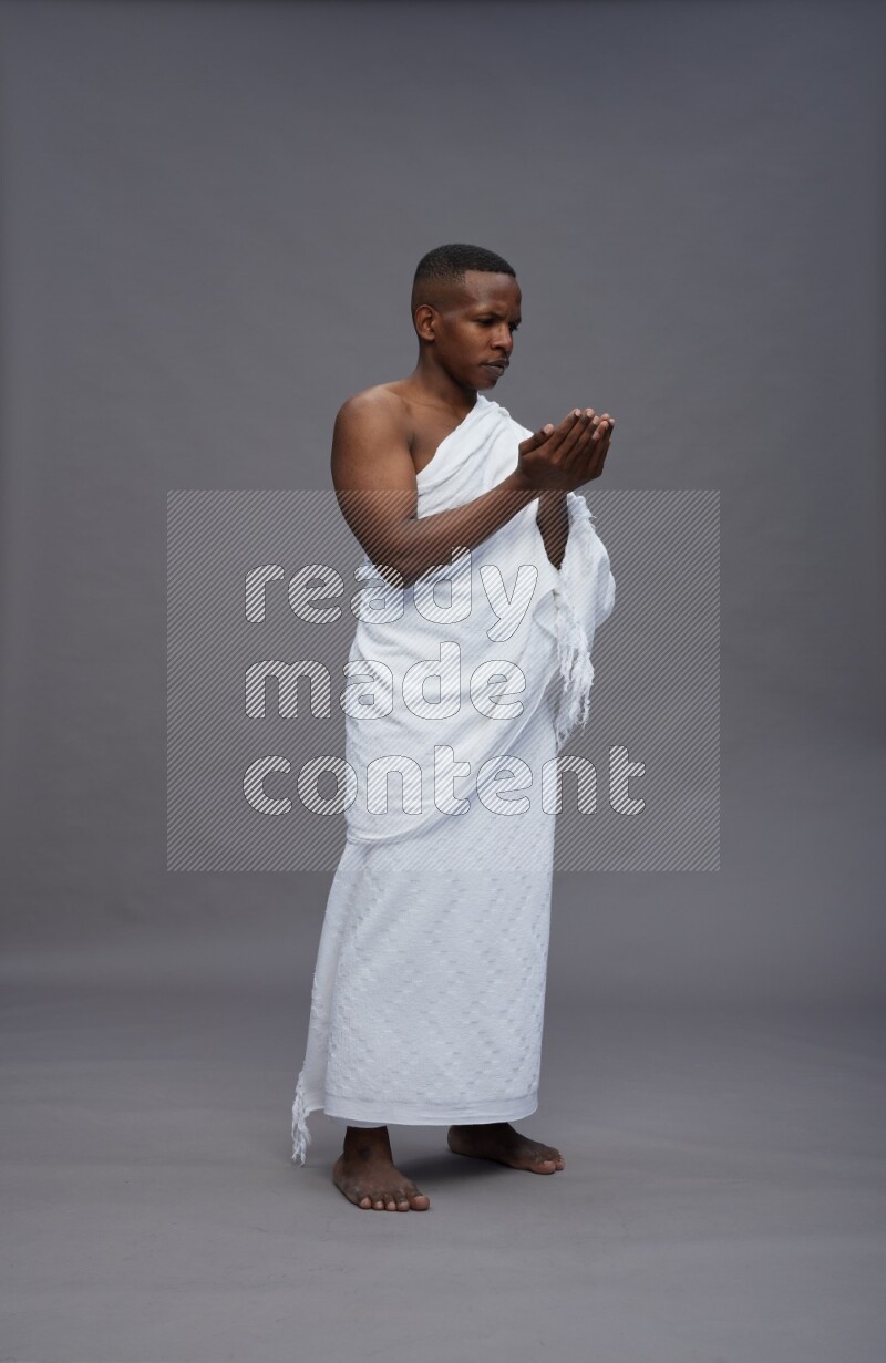 A man wearing Ehram Standing dua'a on gray background