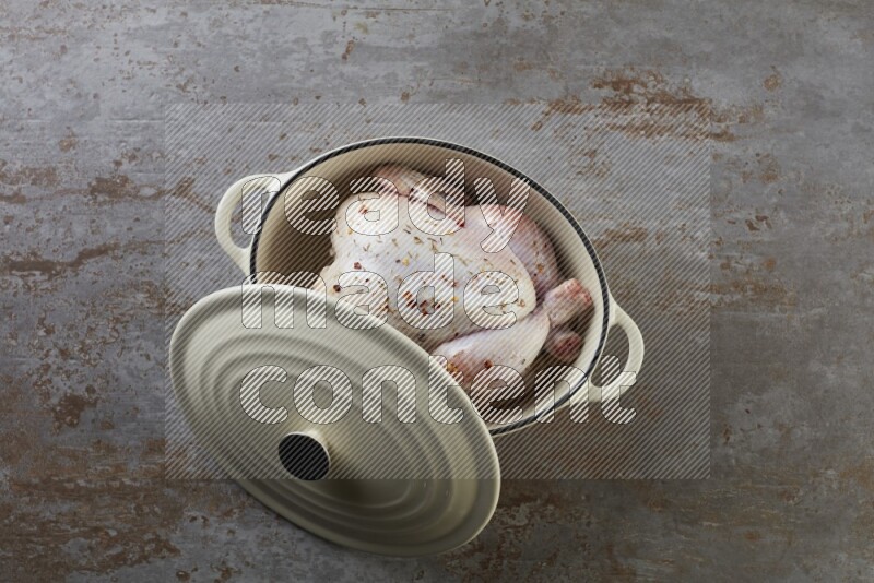 whole raw chicken on in a white ceramic pot direct on a rustic grey background