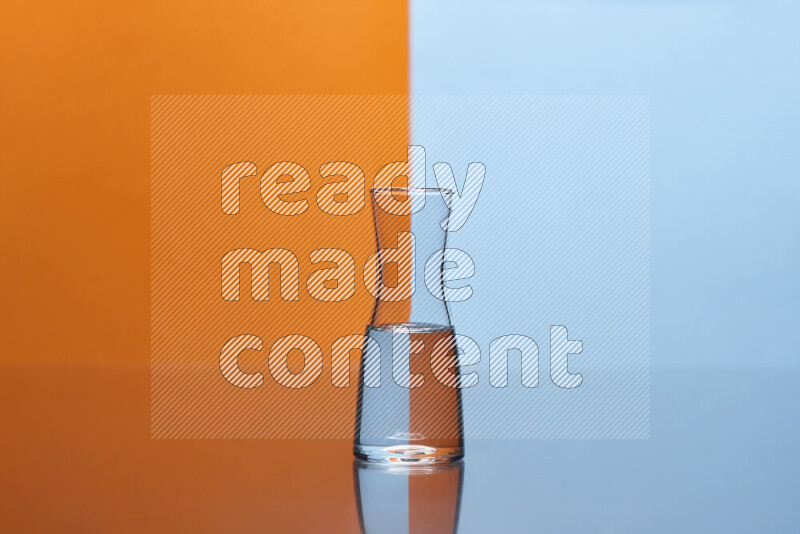 The image features a clear glassware filled with water, set against orange and light blue background