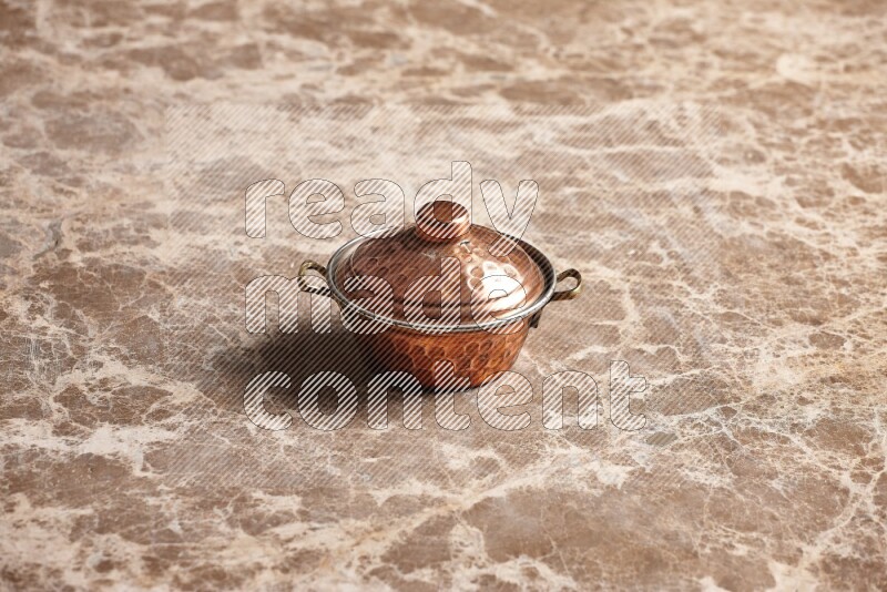 A small copper pot on beige marble background
