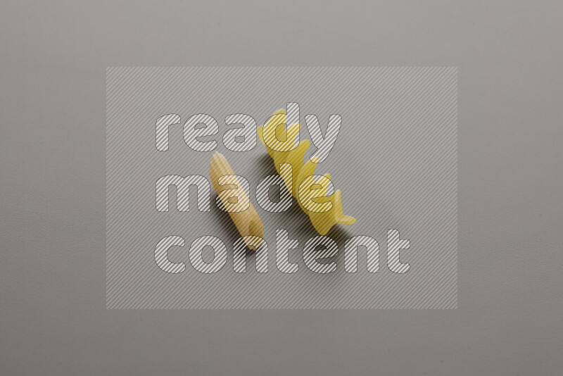 Mini penne pasta with other types of pasta on grey background