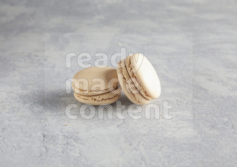 45º Shot of two white marbleCaramel fleur de sel macarons  on white  marble background
