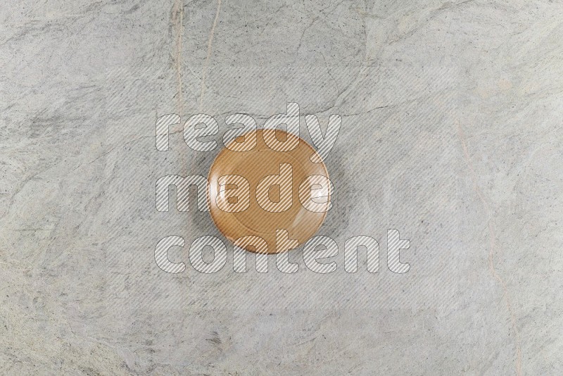 Top View Shot Of A Beige Pottery Circular Plate On Grey Marble Flooring