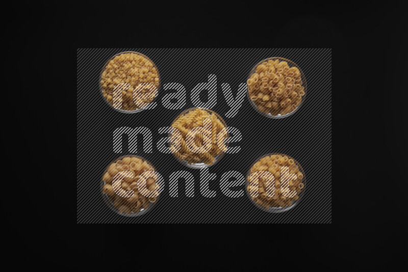 أنواع مختلفة من المعكرونة في أوعية زجاجية علي خلفية سوداء