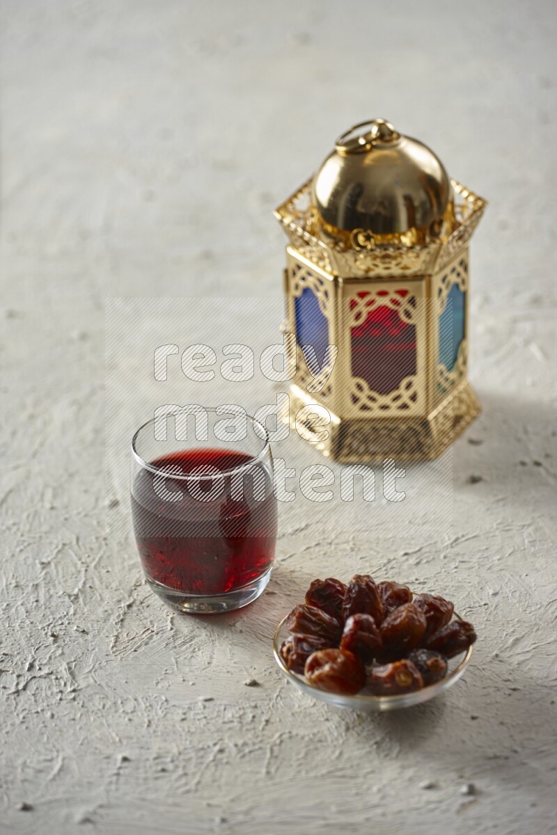 A golden lantern with different drinks, dates, nuts, prayer beads and quran on textured white background